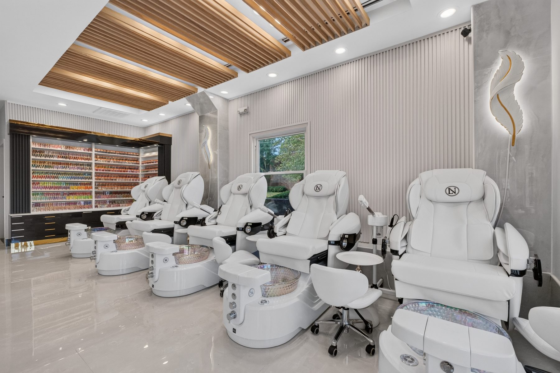 Pedicure chairs beside the full wall of lacquers